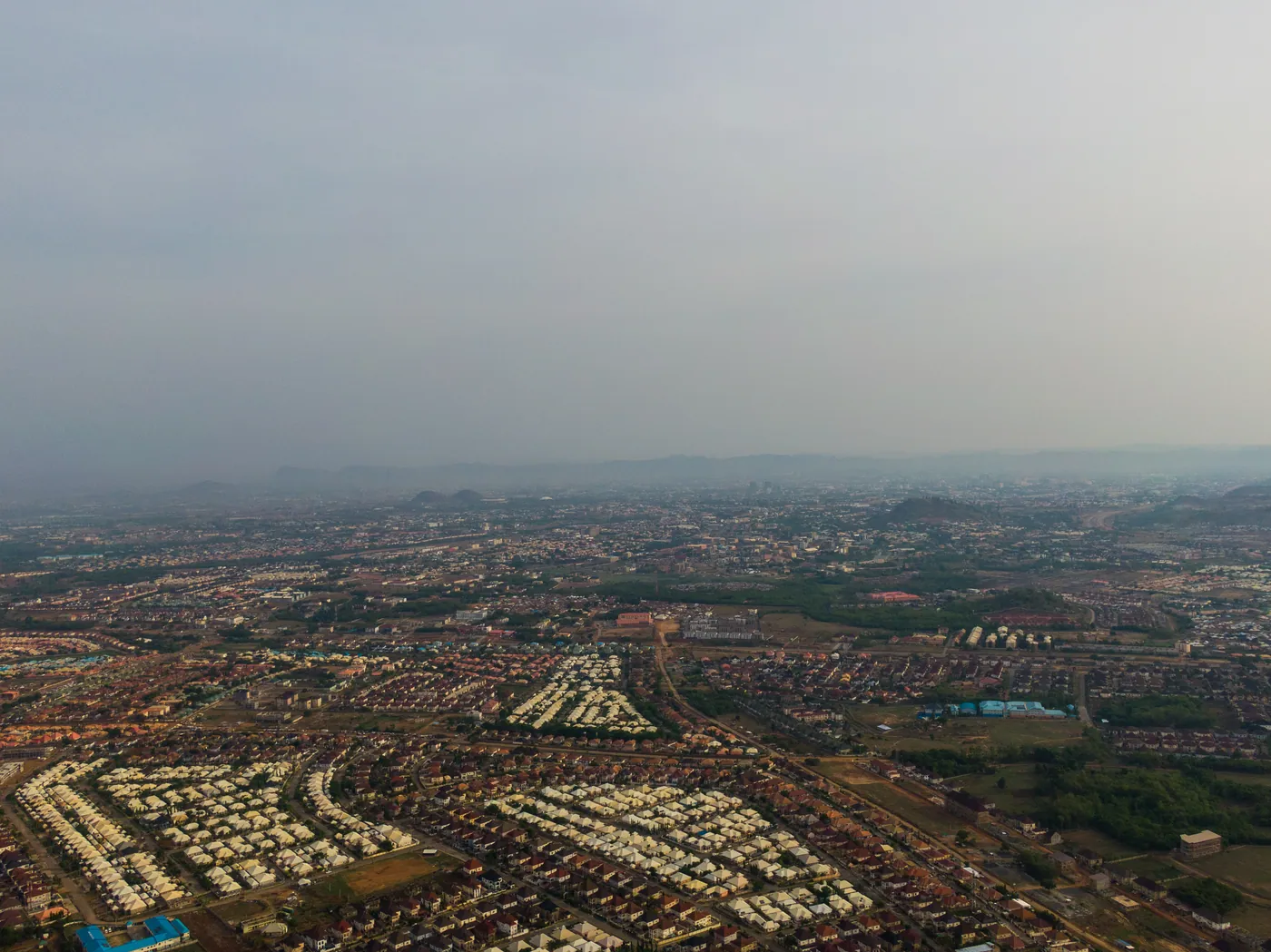 Aerial view of rows of housing estates in Lokogoma district, Abuja, under a hazy sky, April 2024