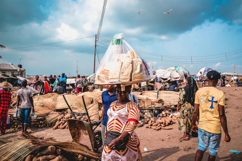Traders carrying goods past heaps of yams and mats at Mile 12 market in Lagos